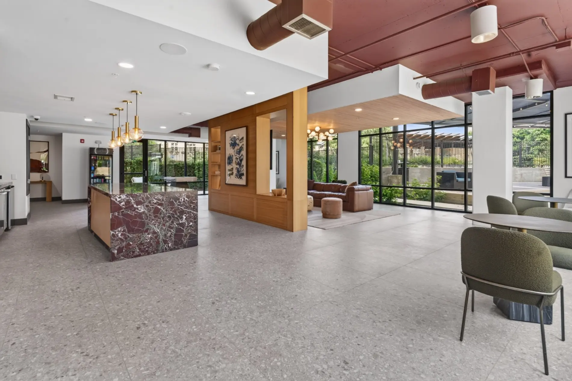 Completed multifamily common area with custom stone bar, wood millwork, lounge seating, and architectural lighting