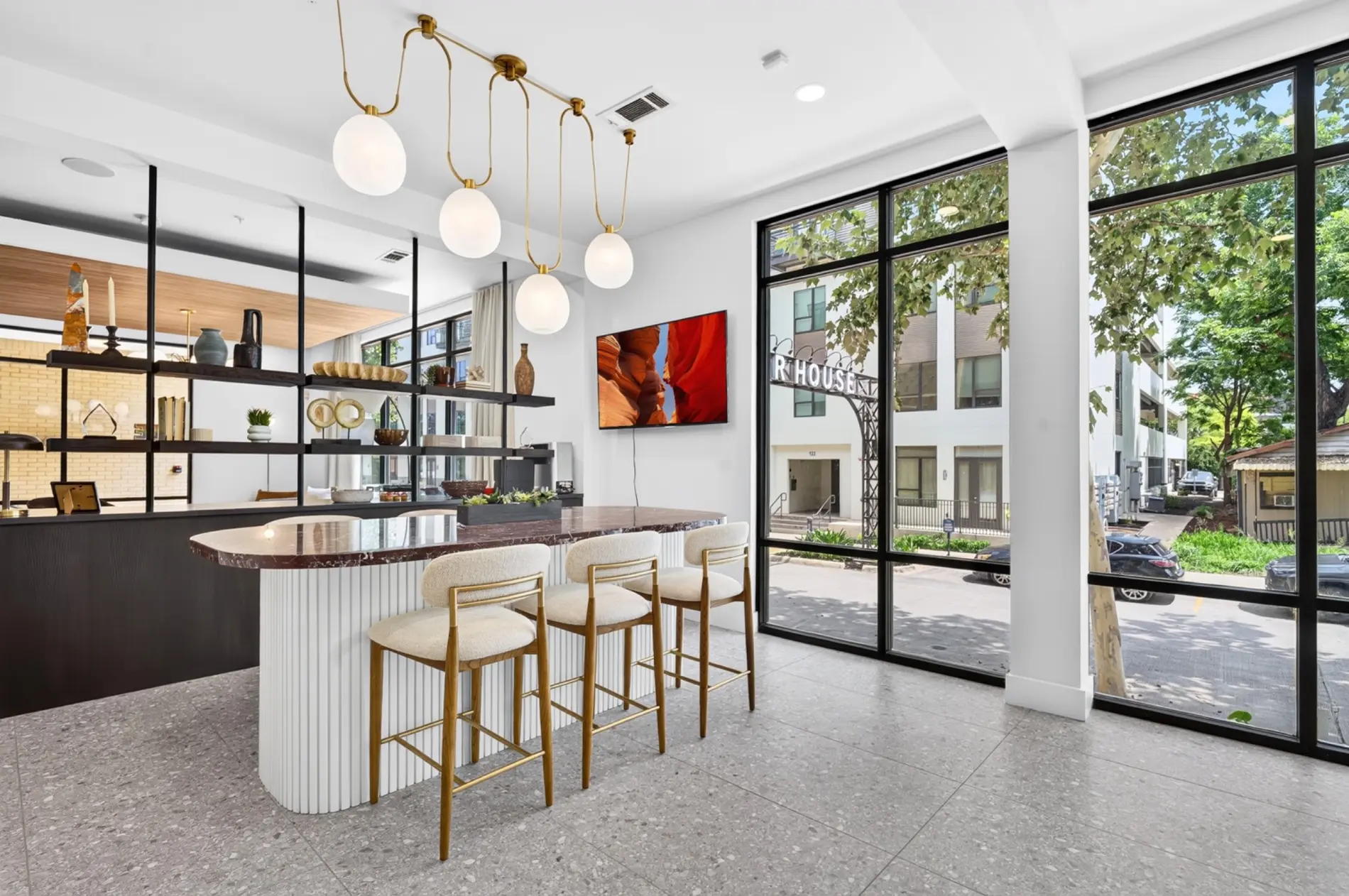 Renovated leasing lounge bar with custom millwork, statement lighting, and floor-to-ceiling windows