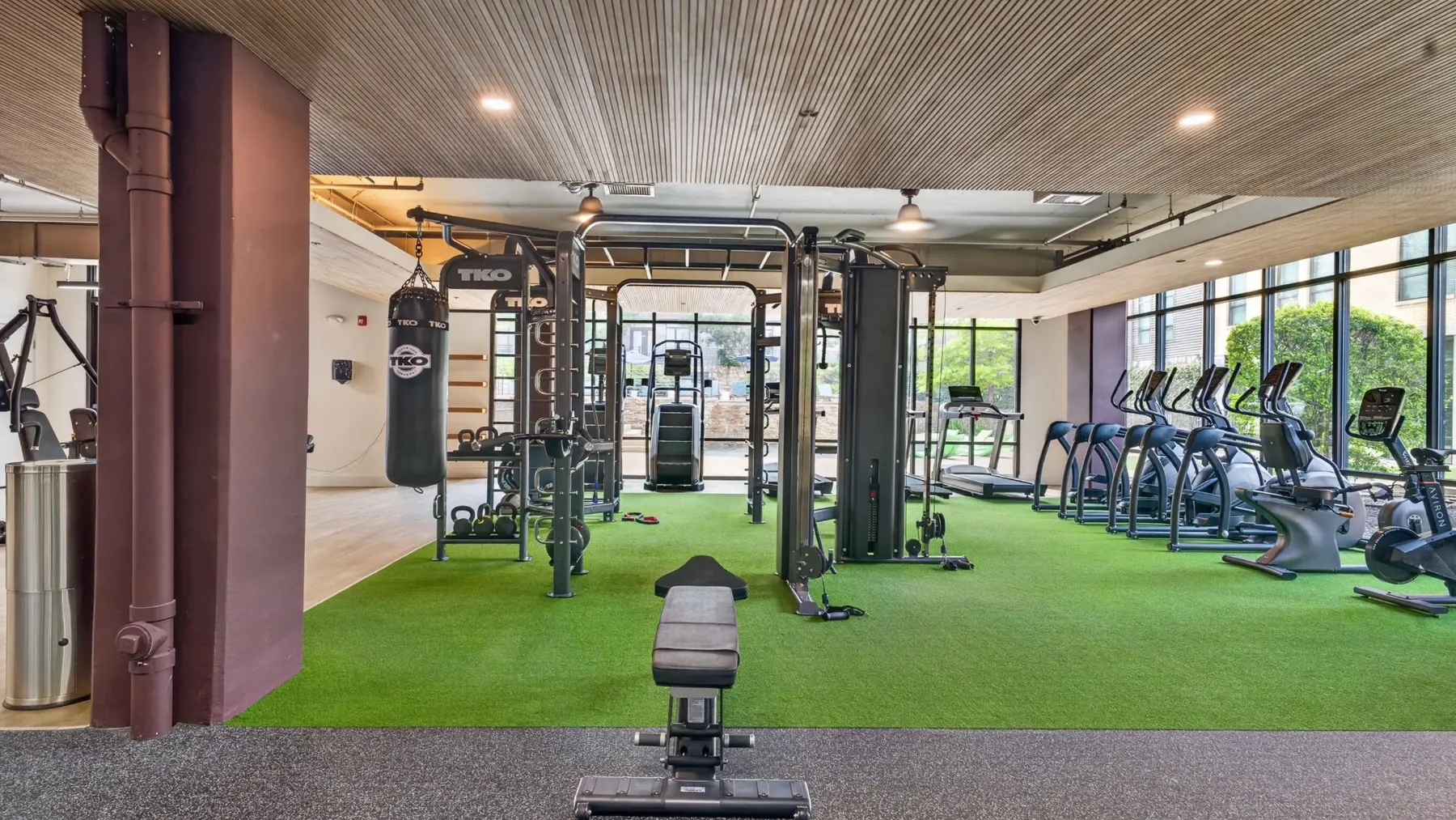 Completed multifamily fitness center training area with turf, strength equipment, and cardio stations