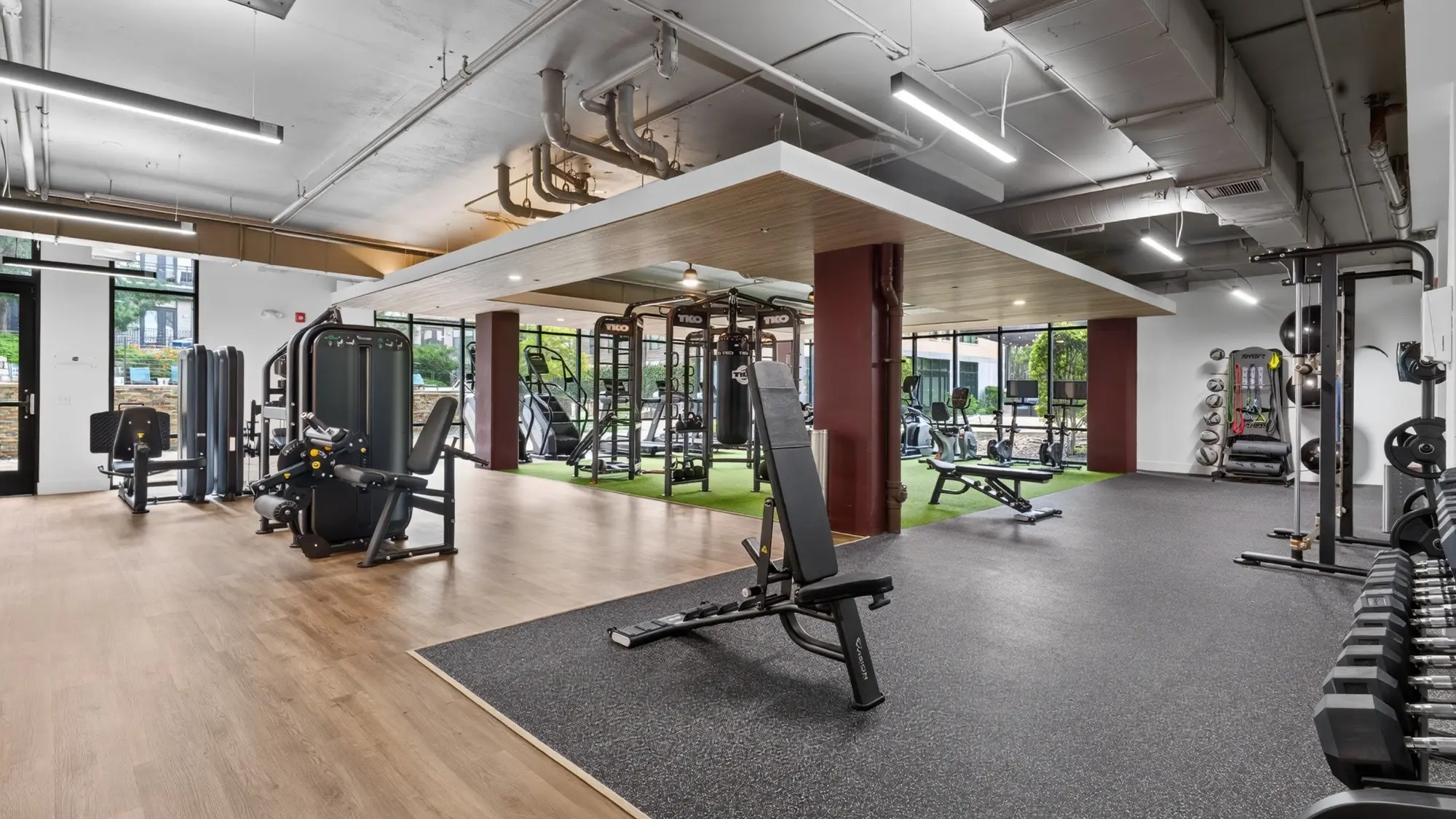 Renovated multifamily fitness center with new flooring, lighting, equipment zones, and architectural canopy