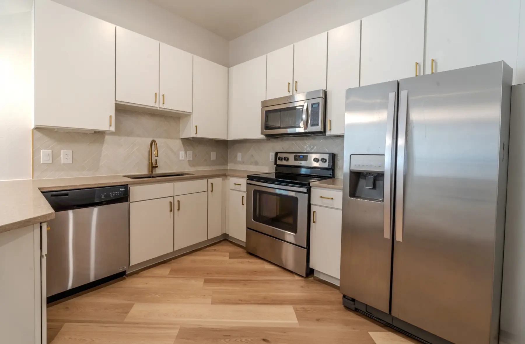 Completed apartment kitchen with new cabinets, backsplash, fixtures, flooring, and appliances