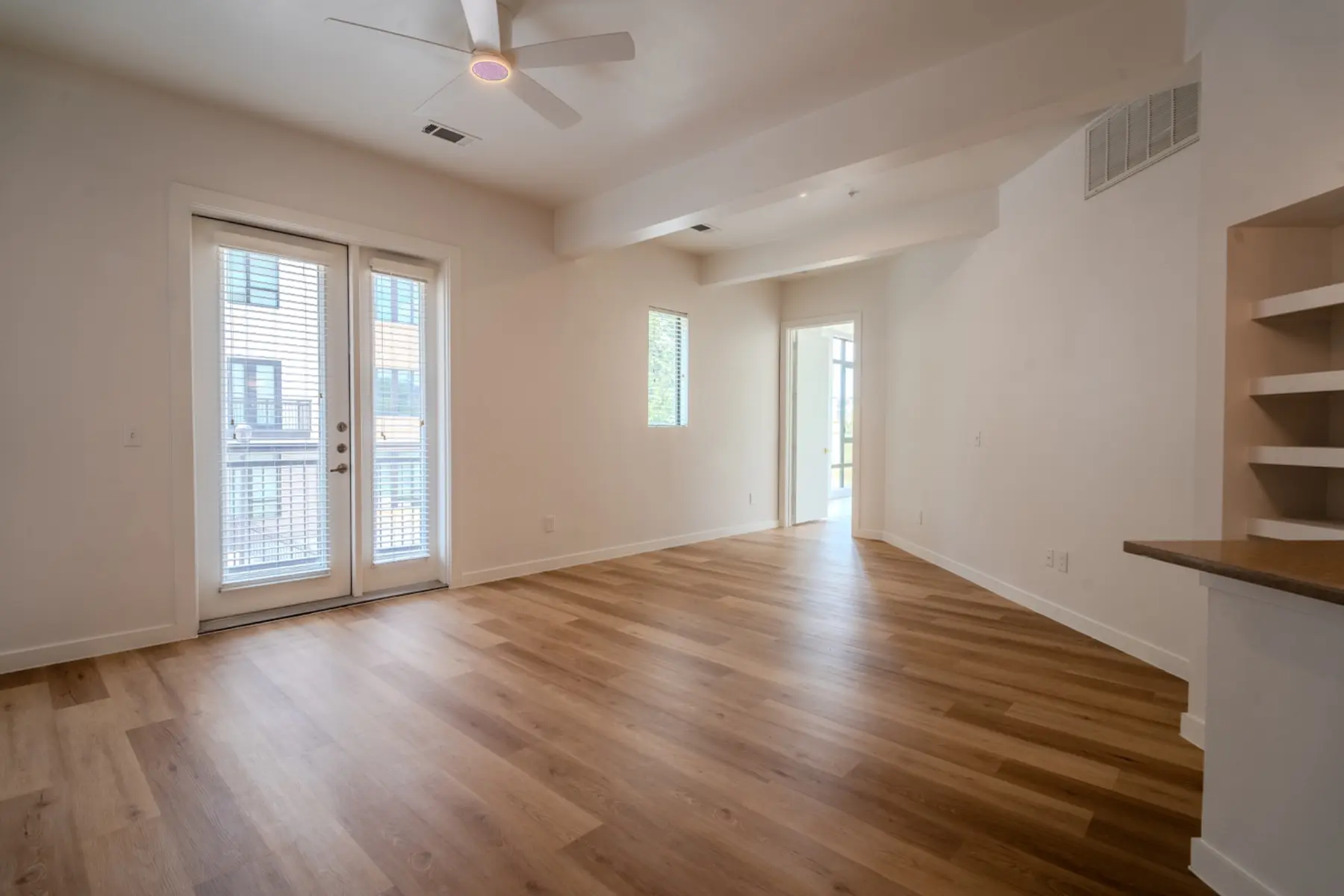Renovated apartment interior with new flooring, paint, trim, lighting, and ceiling fan